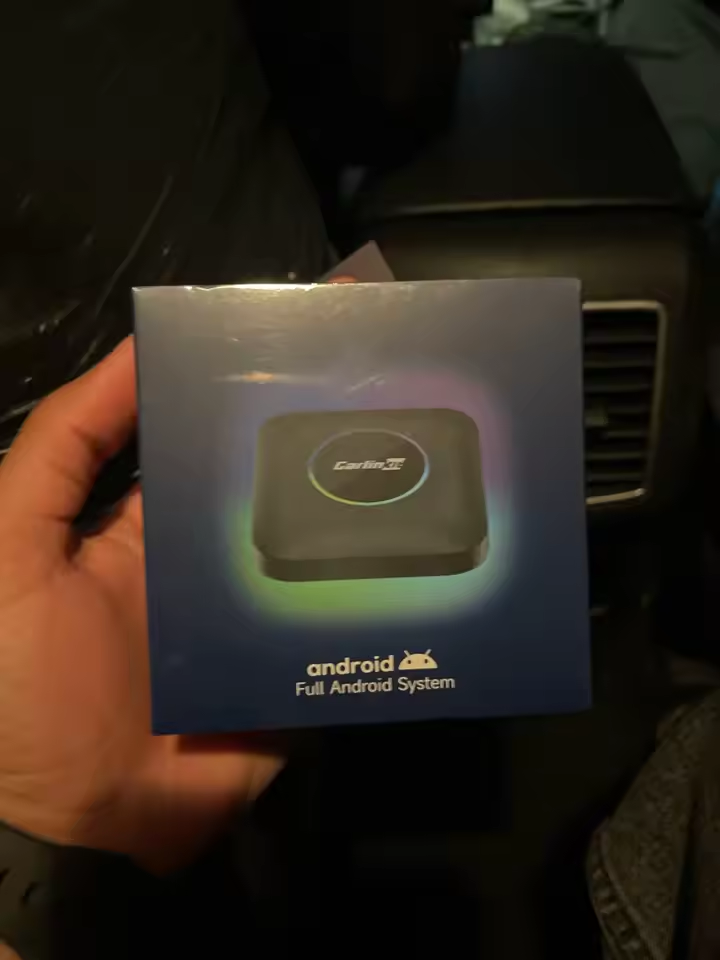 Carlinkit TBox Ambient retail box being unboxed inside a car