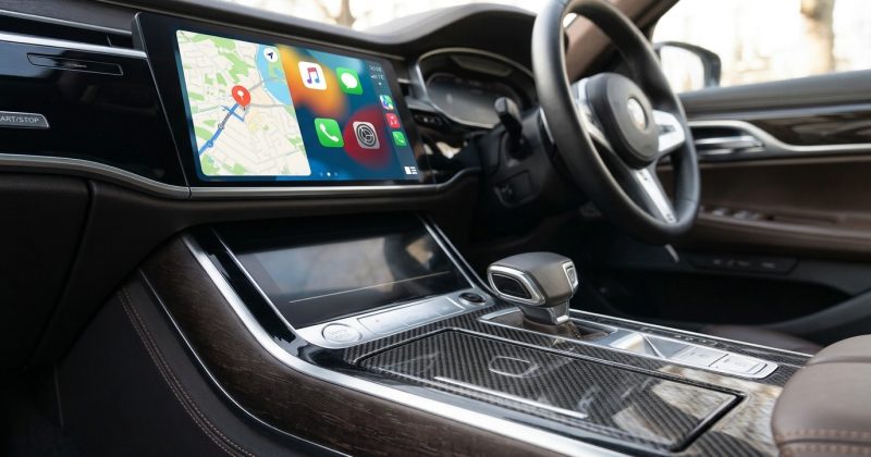 Right-hand-drive car interior with a large touchscreen showing app icons and a small plug-in box on the console